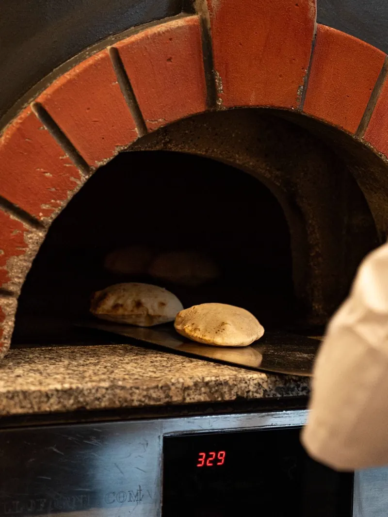 Pan recién horneado saliendo del horno de leña en el restaurante libanés du Liban de Alcobendas